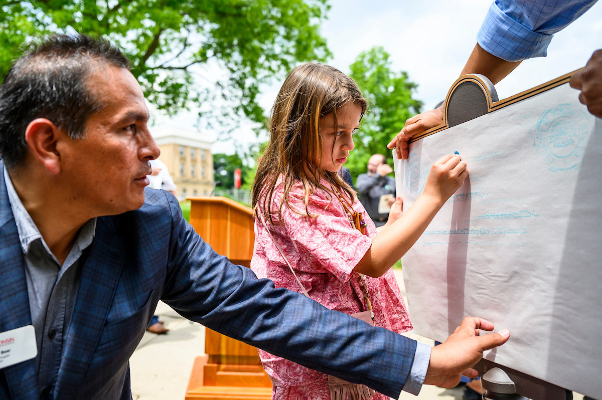 aaron bird bear helps a child with a crayon rubbing as part of the ho chunk dedication ceremony