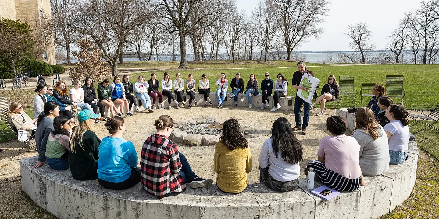 Omar Poler, Indigenous education coordinator in the Office of the Provost, shows a First Nations Cultural Landscape Tour group a map of tribal lands in Wisconsin around the fire circle north of Dejope Residence Hall.