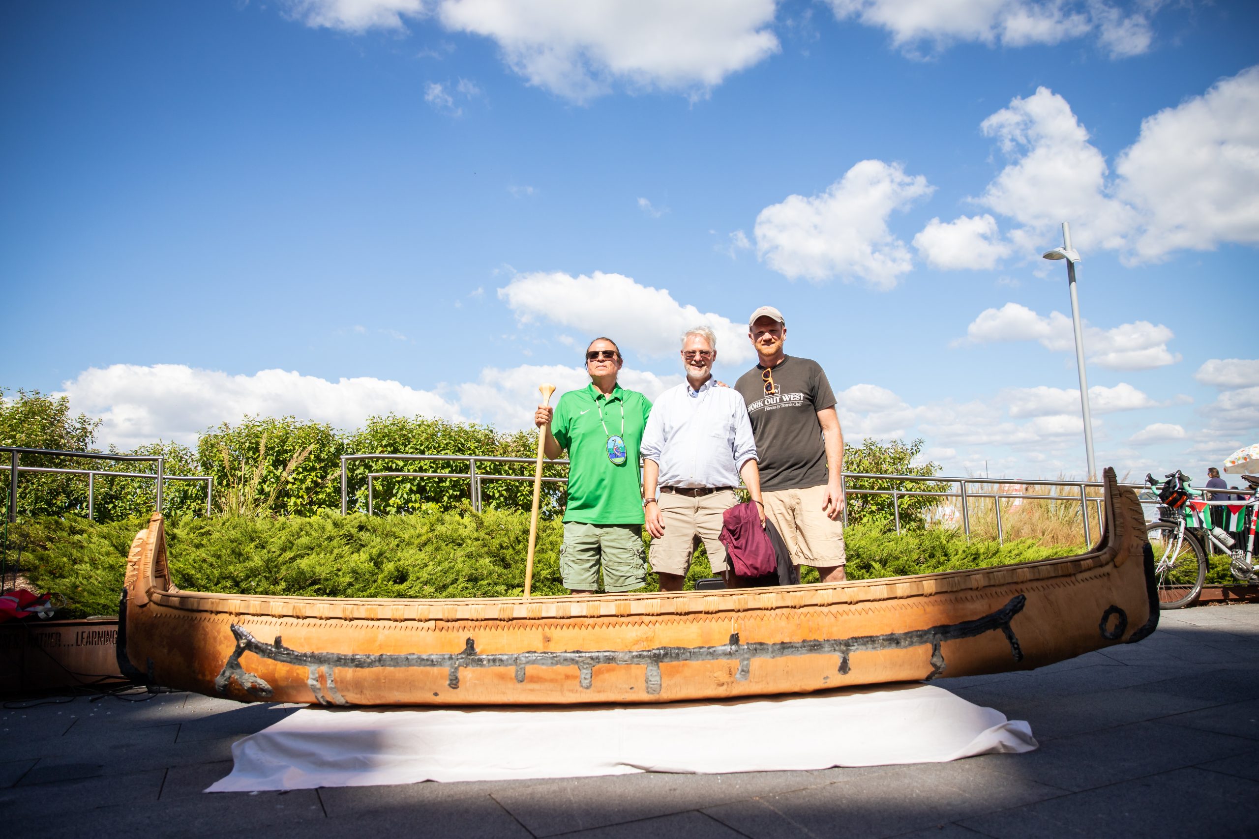 Three men stand behind a canoe